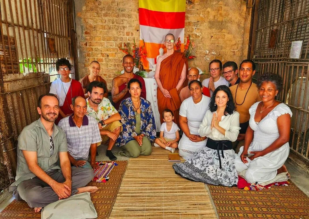 Grupo de personas reunidas ante un altar, con una bhikkhunī de pie